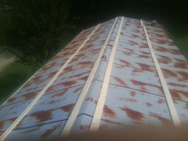 Rusted metal roof panels with new wood purlins before replacement — Storm Damage Roof Repair in Keene by Roofing Brothers